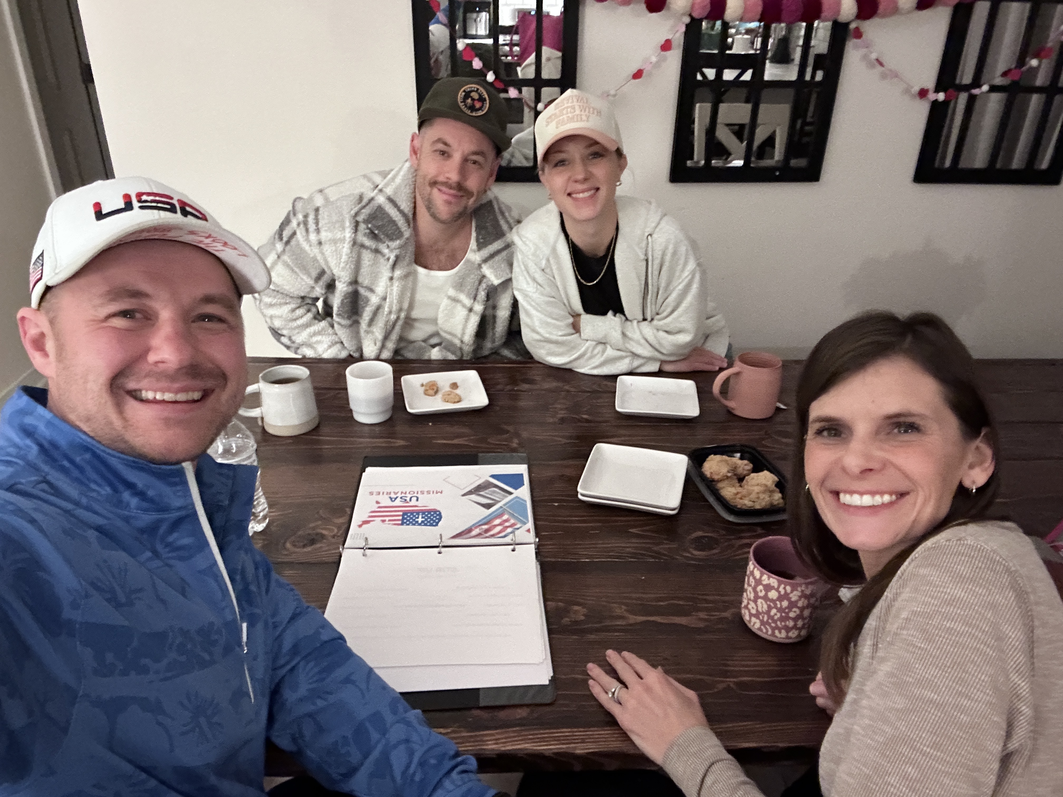 Friends gathered around a home dining table with coffee and cookies during a Kitchen Table Gospel conversation